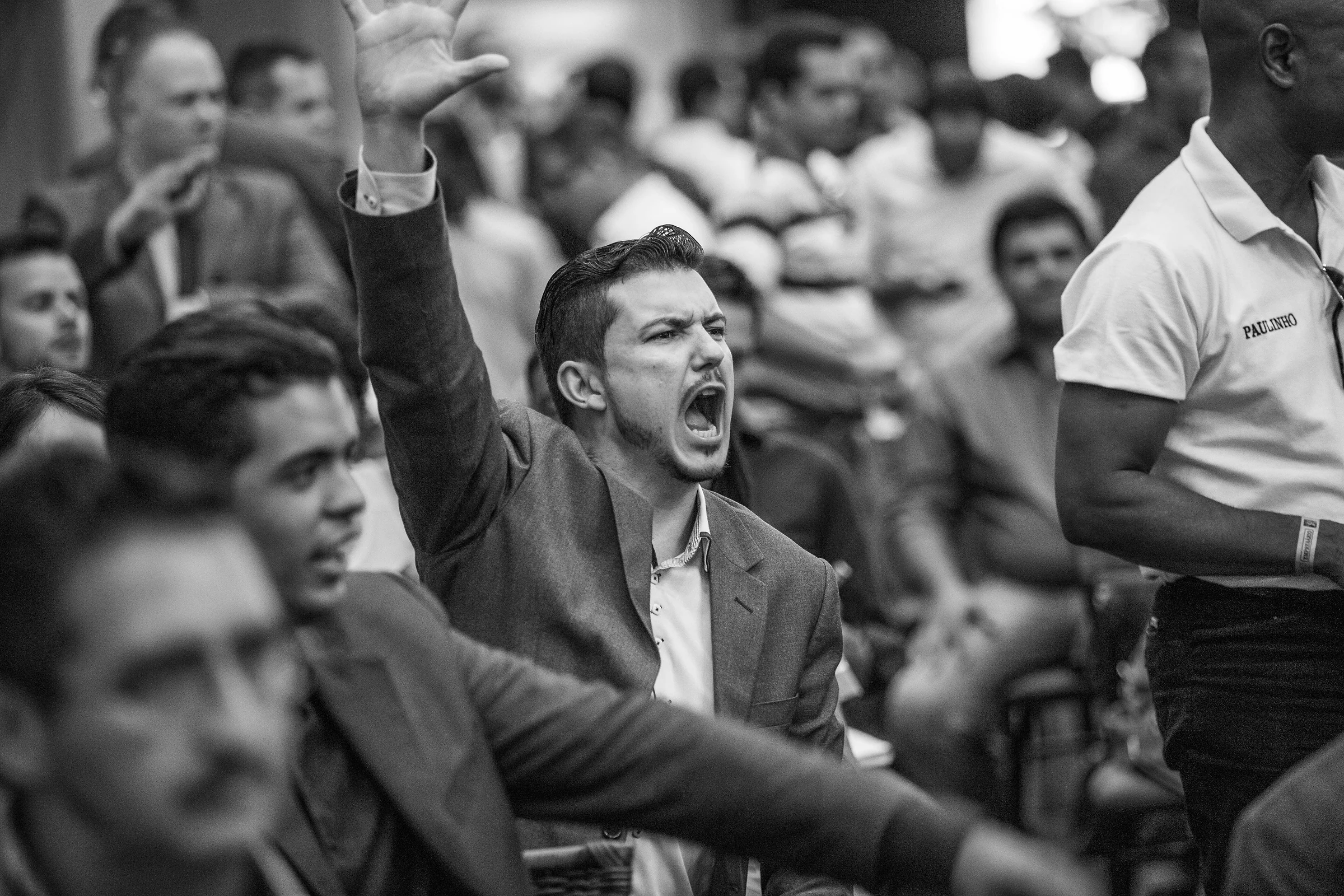 Plateia vibrando em evento corporativo, em preto e branco